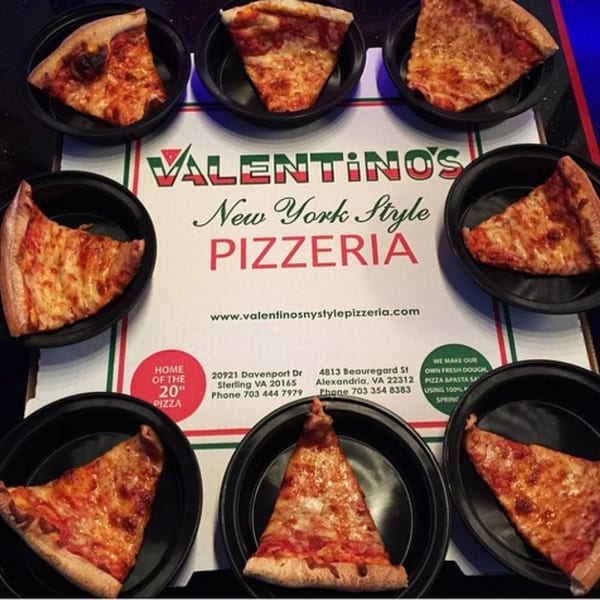 Seven slices of Valentino's New York Style pizza in black dishes surrounding a menu.