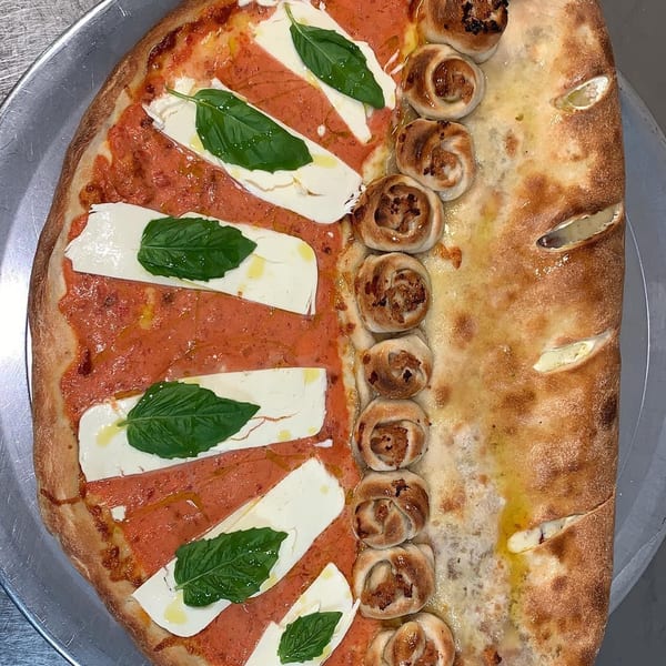 Half pizza with tomato sauce, mozzarella, and basil, half calzone with garlic knots.